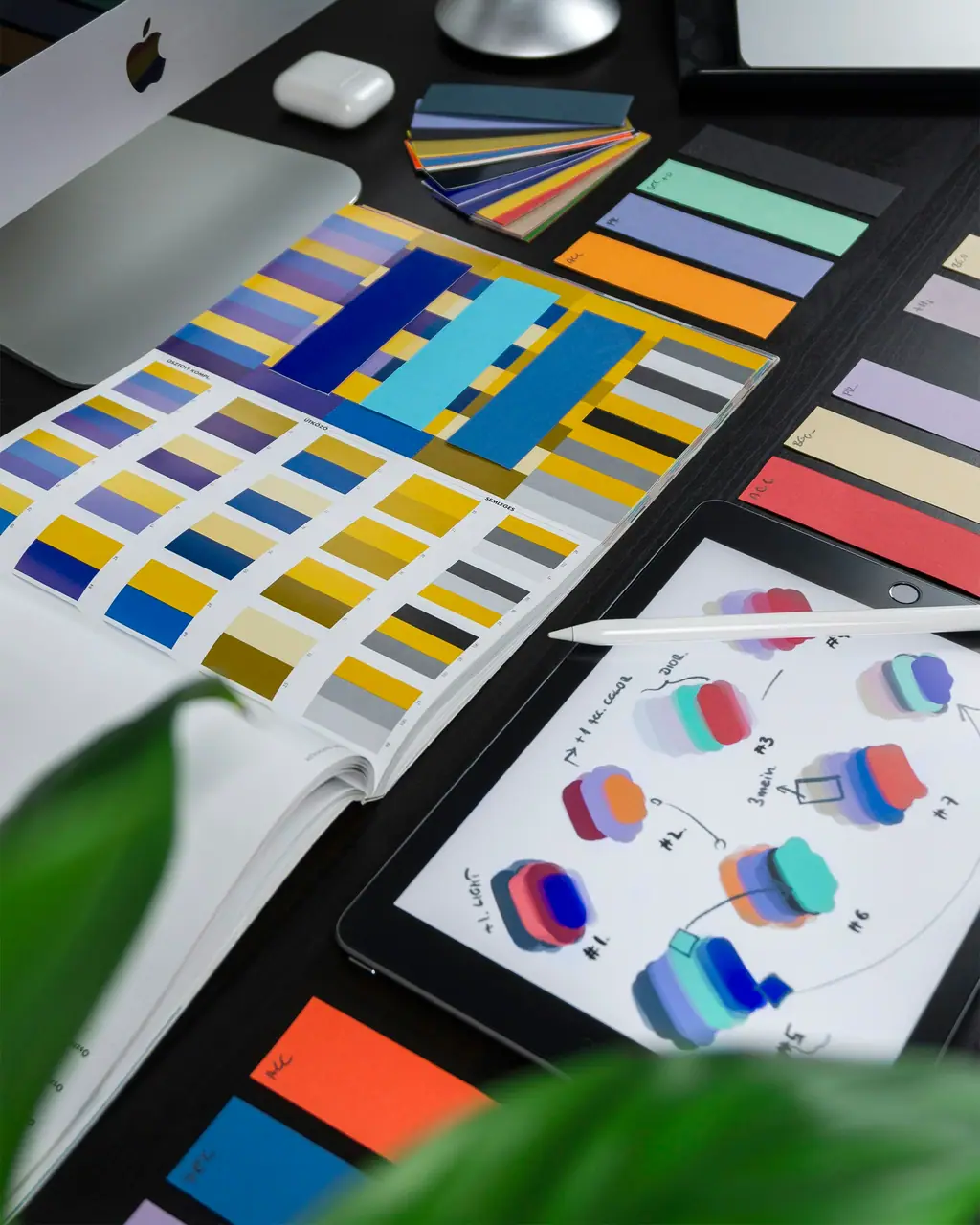 Printed colour swatches and illustrated design studies spread out on a desk