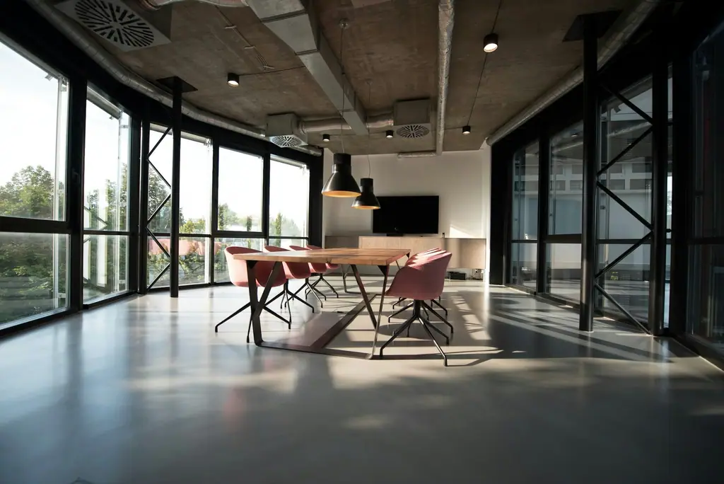 A bright meeting room with a long table and floor-to-ceiling windows