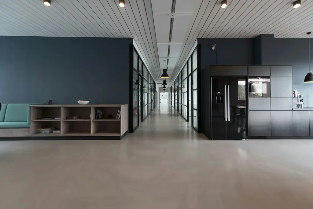 A long, modern office corridor with glass partitions and warm lighting