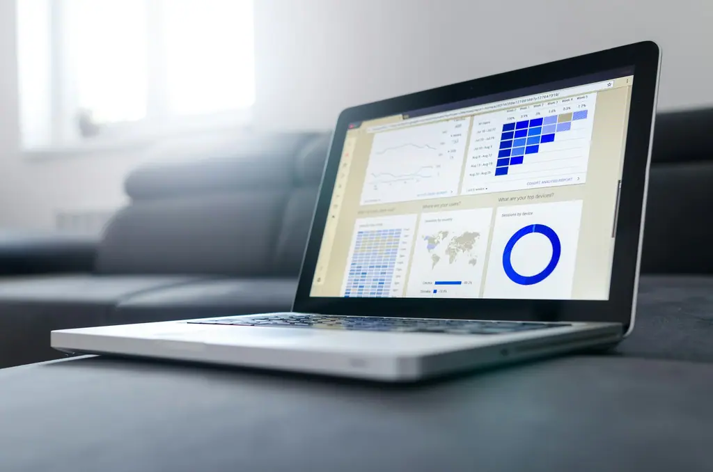 A laptop on a sofa showing a reporting dashboard with charts and a world map